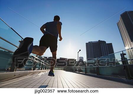 Stock Photo - Young Caucasian man running in metropolitan area. Fotosearch