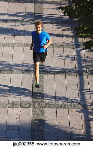 Young Caucasian man running in metropolitan area View Large Photo Image Stock Photo - Young Caucasian man running in metropolitan area. Fotosearch
