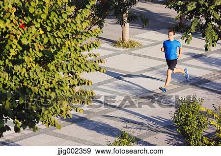 Stock Photo - Young Caucasian man running in metropolitan area. Fotosearch