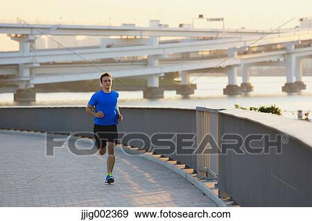 Stock Photo - Young Caucasian man running in metropolitan area. Fotosearch