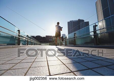 Stock Photograph - Young Caucasian man running in metropolitan area. Fotosearch