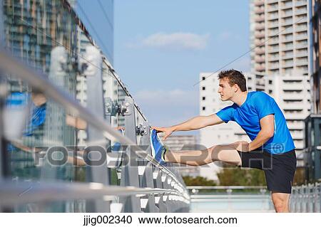 Young Caucasian man stretching in metropolitan area View Large Photo Image Stock Image - Young Caucasian man stretching in metropolitan area. Fotosearch