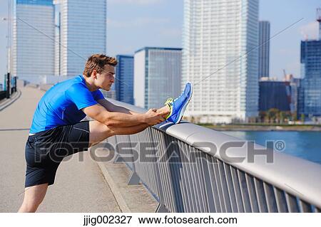 Stock Photo - Young Caucasian man stretching in metropolitan area. Fotosearch