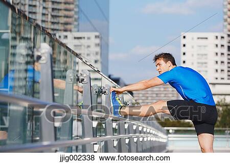 Stock Photo - Young Caucasian man stretching in metropolitan area. Fotosearch