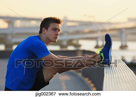 Stock Photo - Young Caucasian man stretching in metropolitan area. Fotosearch