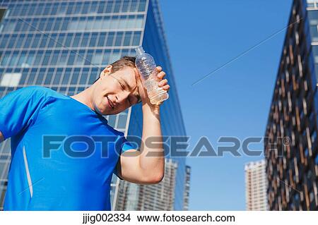 Picture - Young Caucasian man with water in metropolitan area. Fotosearch