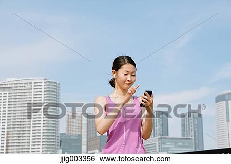 Young Japanese with smartphone during her run downtown Tokyo View Large Photo Image Stock Photograph - Young Japanese with smartphone during her run downtown Tokyo. Fotosearch