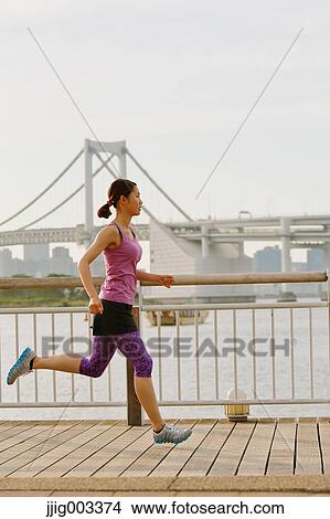 Picture - Young Japanese woman running downtown Tokyo. Fotosearch