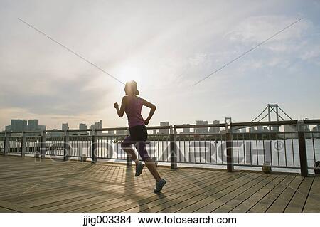 Picture - Young Japanese woman running downtown Tokyo. Fotosearch