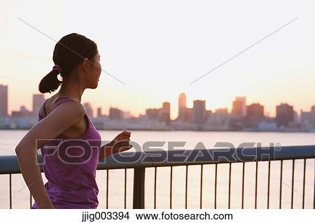 Picture - Young Japanese woman running downtown Tokyo. Fotosearch