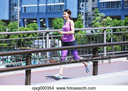 Picture - Young Japanese woman running downtown Tokyo. Fotosearch