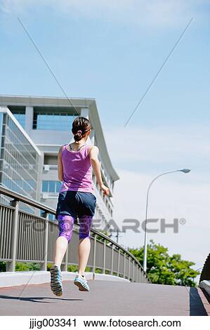 Stock Image - Young Japanese woman running downtown Tokyo. Fotosearch