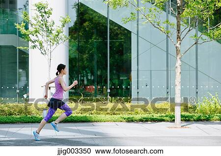 Stock Image - Young Japanese woman running downtown Tokyo. Fotosearch