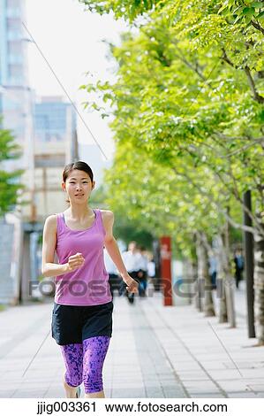 Stock Image - Young Japanese woman running downtown Tokyo. Fotosearch