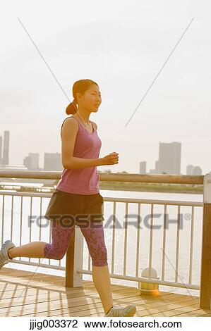 Stock Image - Young Japanese woman running downtown Tokyo. Fotosearch