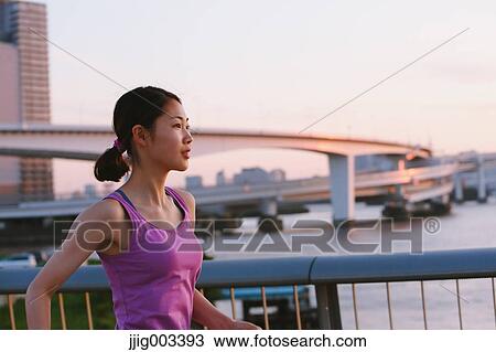 Stock Image - Young Japanese woman running downtown Tokyo. Fotosearch
