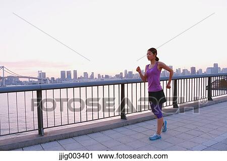 Stock Image - Young Japanese woman running downtown Tokyo. Fotosearch