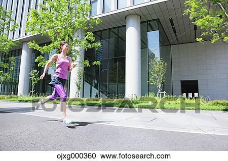 Stock Image - Young Japanese woman running downtown Tokyo. Fotosearch