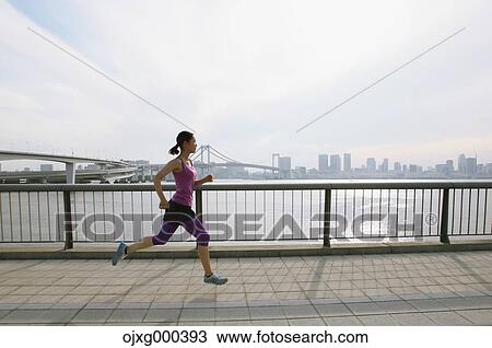 Stock Image - Young Japanese woman running downtown Tokyo. Fotosearch