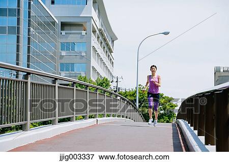 Stock Photo - Young Japanese woman running downtown Tokyo. Fotosearch
