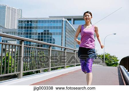 Stock Photo - Young Japanese woman running downtown Tokyo. Fotosearch