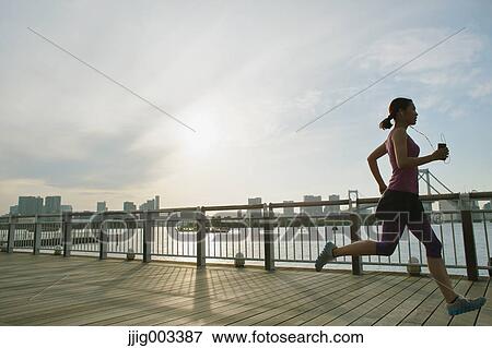 Stock Photo - Young Japanese woman running downtown Tokyo. Fotosearch