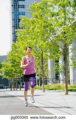 Stock Photography - Young Japanese woman running downtown Tokyo. Fotosearch