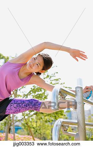 Stock Image - Young Japanese woman stretching before her run downtown Tokyo. Fotosearch