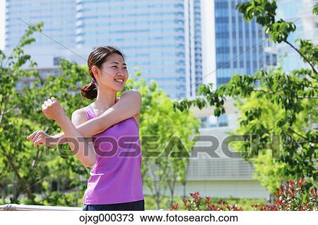 Stock Image - Young Japanese woman stretching before her run downtown Tokyo. Fotosearch