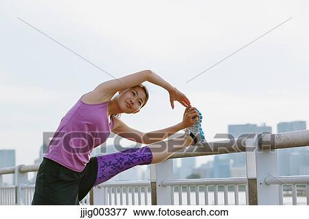Stock Photo - Young Japanese woman stretching before her run downtown Tokyo. Fotosearch