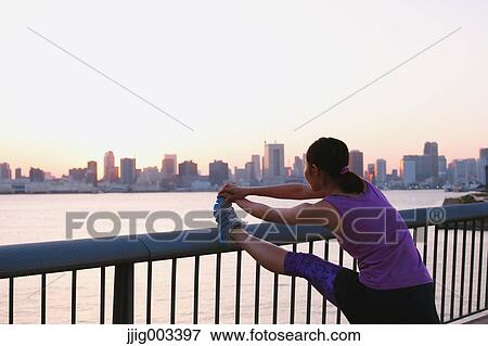 Stock Photo - Young Japanese woman stretching before her run downtown Tokyo. Fotosearch