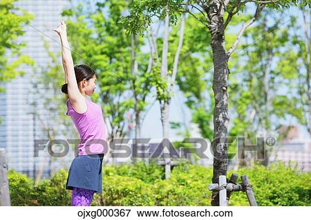 Stock Photo - Young Japanese woman stretching before her run downtown Tokyo. Fotosearch