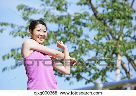 Stock Photo - Young Japanese woman stretching before her run downtown Tokyo. Fotosearch