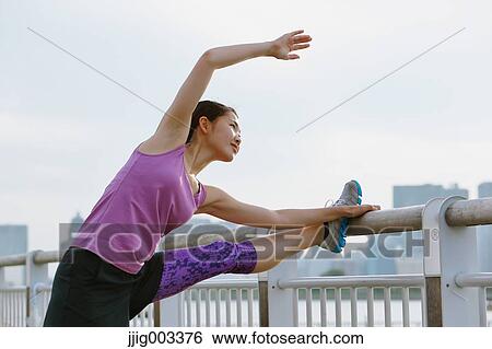 Stock Photograph - Young Japanese woman stretching before her run downtown Tokyo. Fotosearch