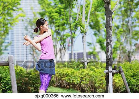 Stock Photograph - Young Japanese woman stretching before her run downtown Tokyo. Fotosearch
