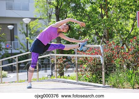 Stock Photograph - Young Japanese woman stretching before her run downtown Tokyo. Fotosearch