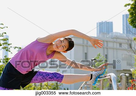 Stock Photography - Young Japanese woman stretching before her run downtown Tokyo. Fotosearch