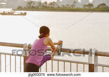 Stock Photography - Young Japanese woman stretching before her run downtown Tokyo. Fotosearch