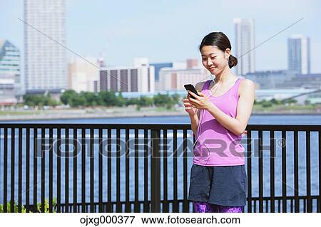 Young Japanese woman with smartphone before her run downtown Tokyo View Large Photo Image Stock Photo - Young Japanese woman with smartphone before her run downtown Tokyo. Fotosearch