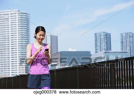 Young Japanese woman with smartphone before her run downtown Tokyo View Large Photo Image Stock Photo - Young Japanese woman with smartphone before her run downtown Tokyo. Fotosearch