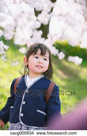 Young smiling Japanese girl enjoying cherry blossoms in a city park View Large Photo Image Picture - Young smiling Japanese girl enjoying cherry blossoms in a city park. Fotosearch