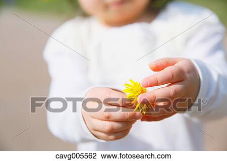 Stock Image - Young smiling Japanese girl enjoying cherry blossoms in a city park. Fotosearch