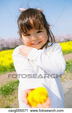 Stock Image - Young smiling Japanese girl enjoying cherry blossoms in a city park. Fotosearch