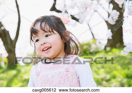 Young smiling Japanese girl enjoying cherry blossoms in a city park View Large Photo Image Stock Image - Young smiling Japanese girl enjoying cherry blossoms in a city park. Fotosearch
