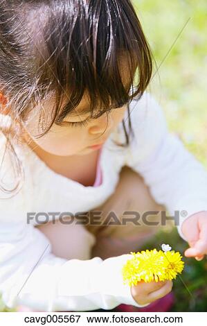 Stock Photo - Young smiling Japanese girl enjoying cherry blossoms in a city park. Fotosearch