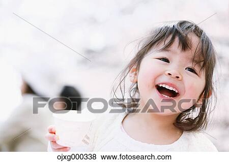 Young smiling Japanese girl enjoying cherry blossoms in a city park View Large Photo Image Stock Photo - Young smiling Japanese girl enjoying cherry blossoms in a city park. Fotosearch