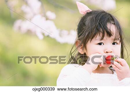 Stock Photo - Young smiling Japanese girl enjoying cherry blossoms in a city park. Fotosearch