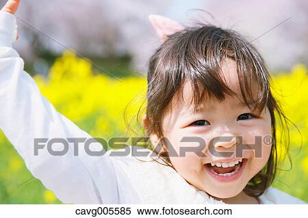 Stock Photography - Young smiling Japanese girl enjoying cherry blossoms in a city park. Fotosearch