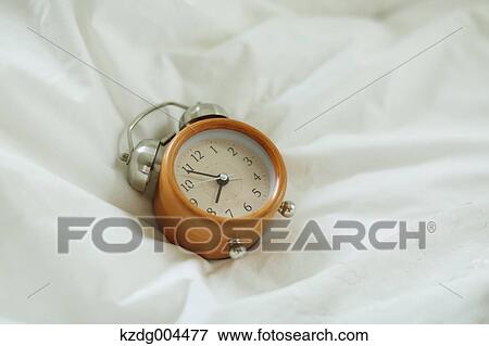 Stock Photo - Alarm clock on bed. Fotosearch