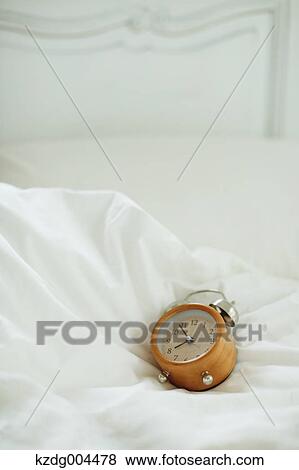 Stock Photo - Alarm clock on bed. Fotosearch